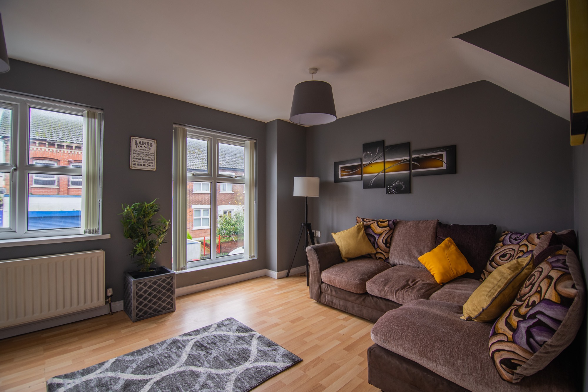 Shared lounge with corner sofa, yellow cushions and windows